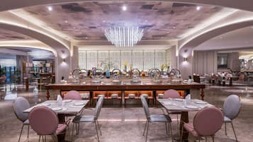 A spacious dining area with a central buffet, elegant chairs, and a modern chandelier.