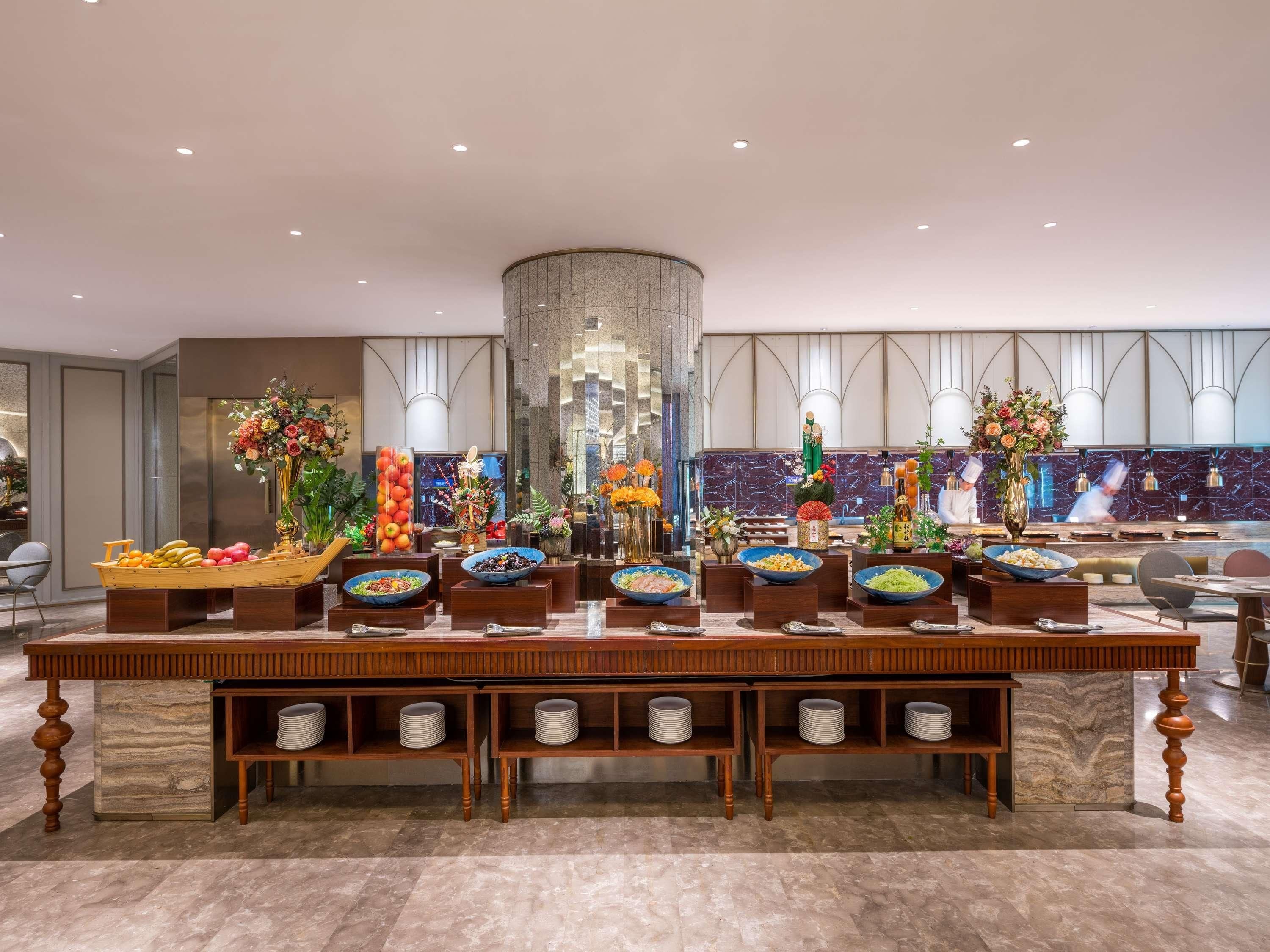 Een buffetopstelling met diverse etenswaren en decoratieve elementen in een moderne hotelomgeving.