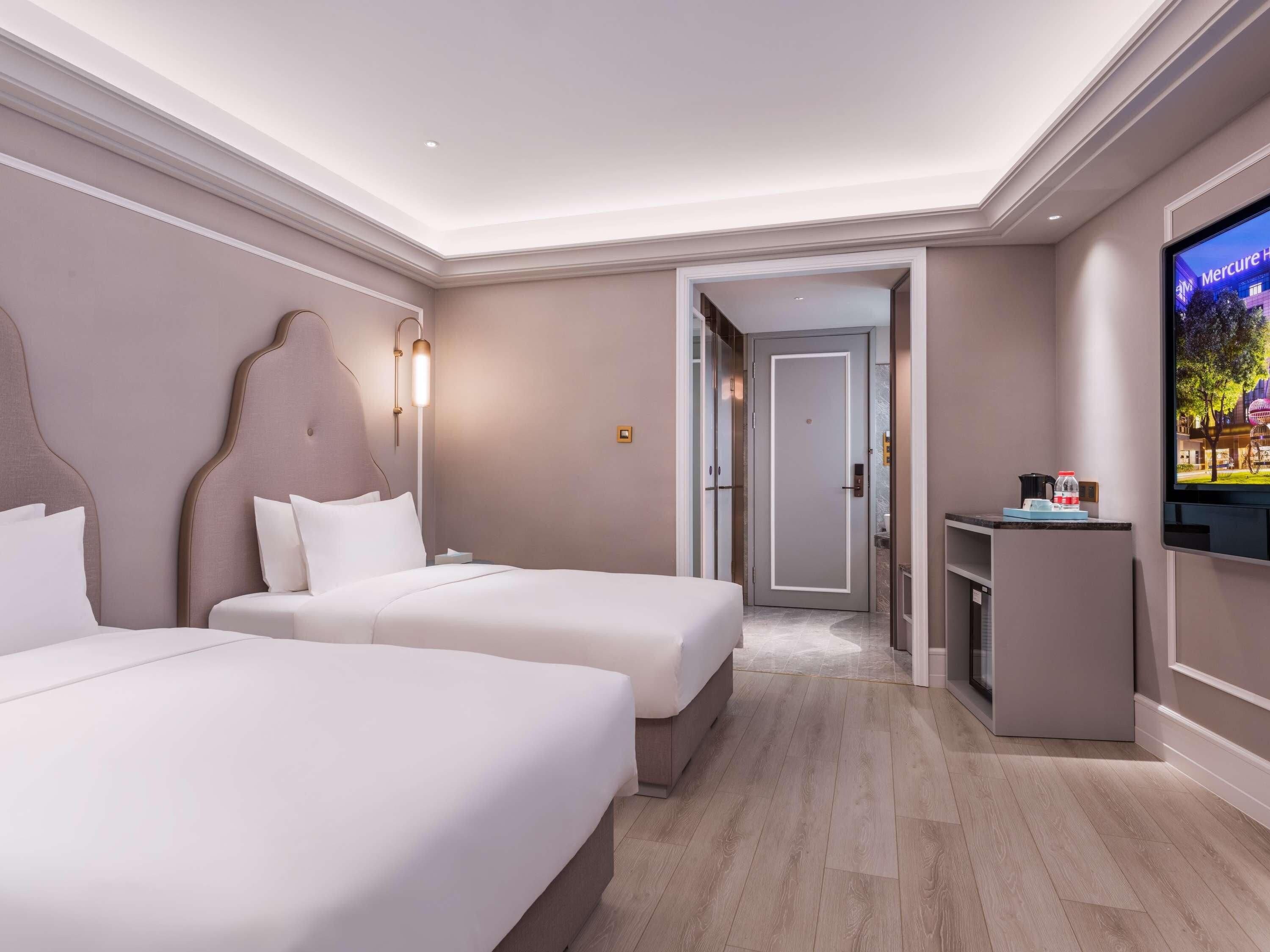 A hotel room with two beds, a TV, and a desk.