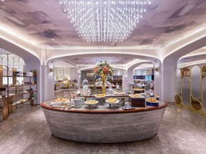 A luxurious hotel lobby with a central round buffet, elegant lighting, and a modern design.