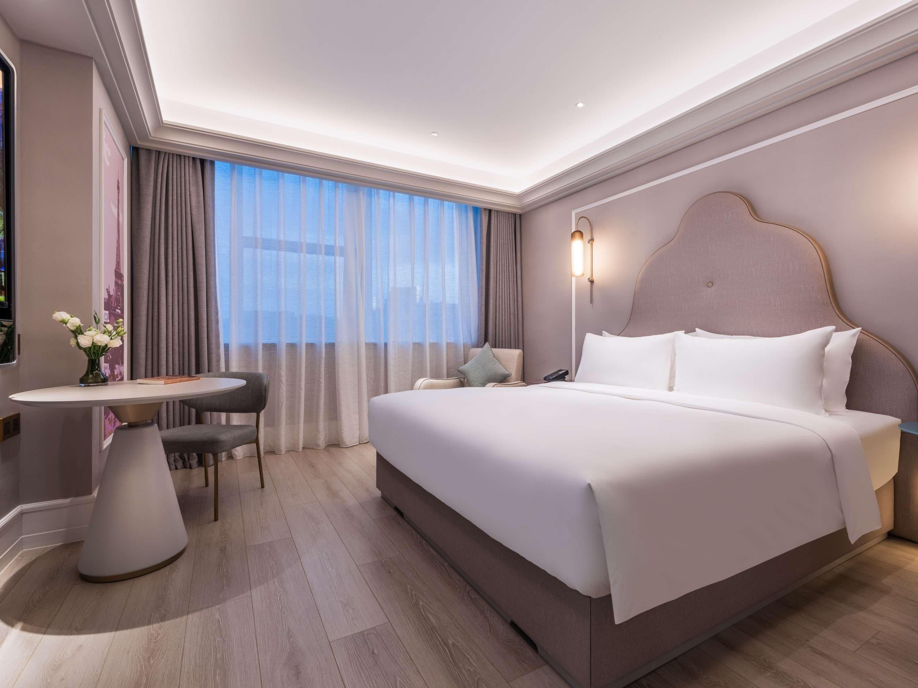 A modern hotel room with a large bed, a desk, and a chair.