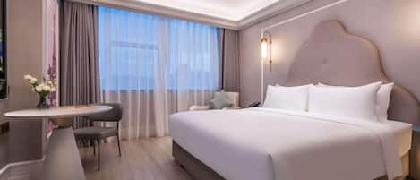 A modern hotel room with a large bed, a desk, and a chair.