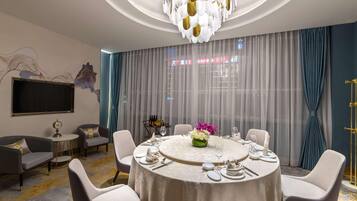 A modern dining room with a round table, white chairs, and a chandelier.