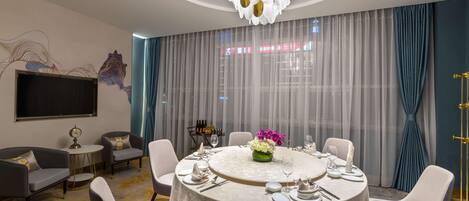 Un comedor moderno con una mesa redonda, sillas blancas y una lámpara de araña.