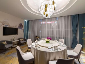A modern dining room with a round table, white chairs, and a chandelier. - Mercure Shijiazhuang People Square (Shijiazhuang)