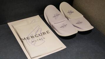 Un par de zapatillas de hotel Mercure y un folleto.