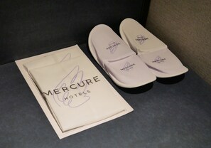 Un par de zapatillas de hotel Mercure y un folleto.