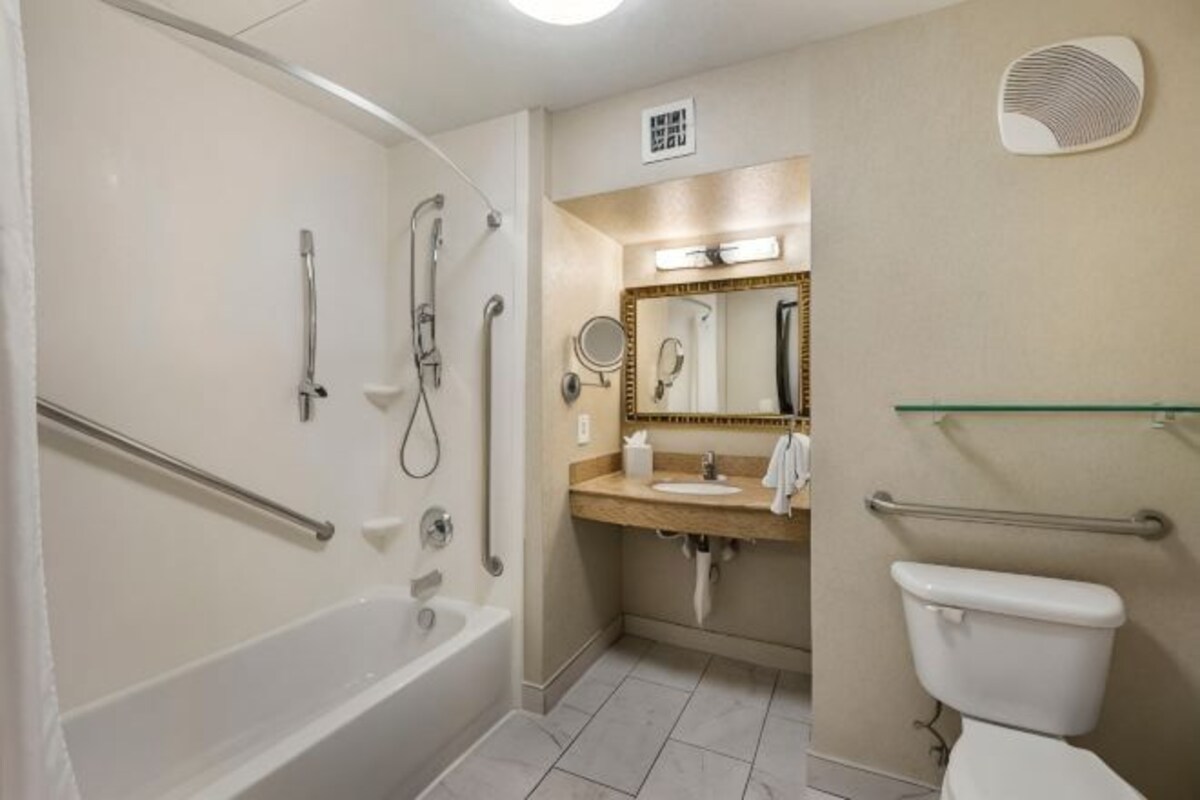 A bathroom with a bathtub, shower, toilet, and vanity with a mirror.
