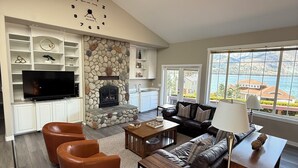 Ein geräumiges Wohnzimmer mit Kamin aus Stein, Ledersofas und einem großen Fernseher.