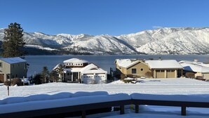 Ein verschneites Wohngebiet mit Häusern und einem See, umgeben von Bergen.
