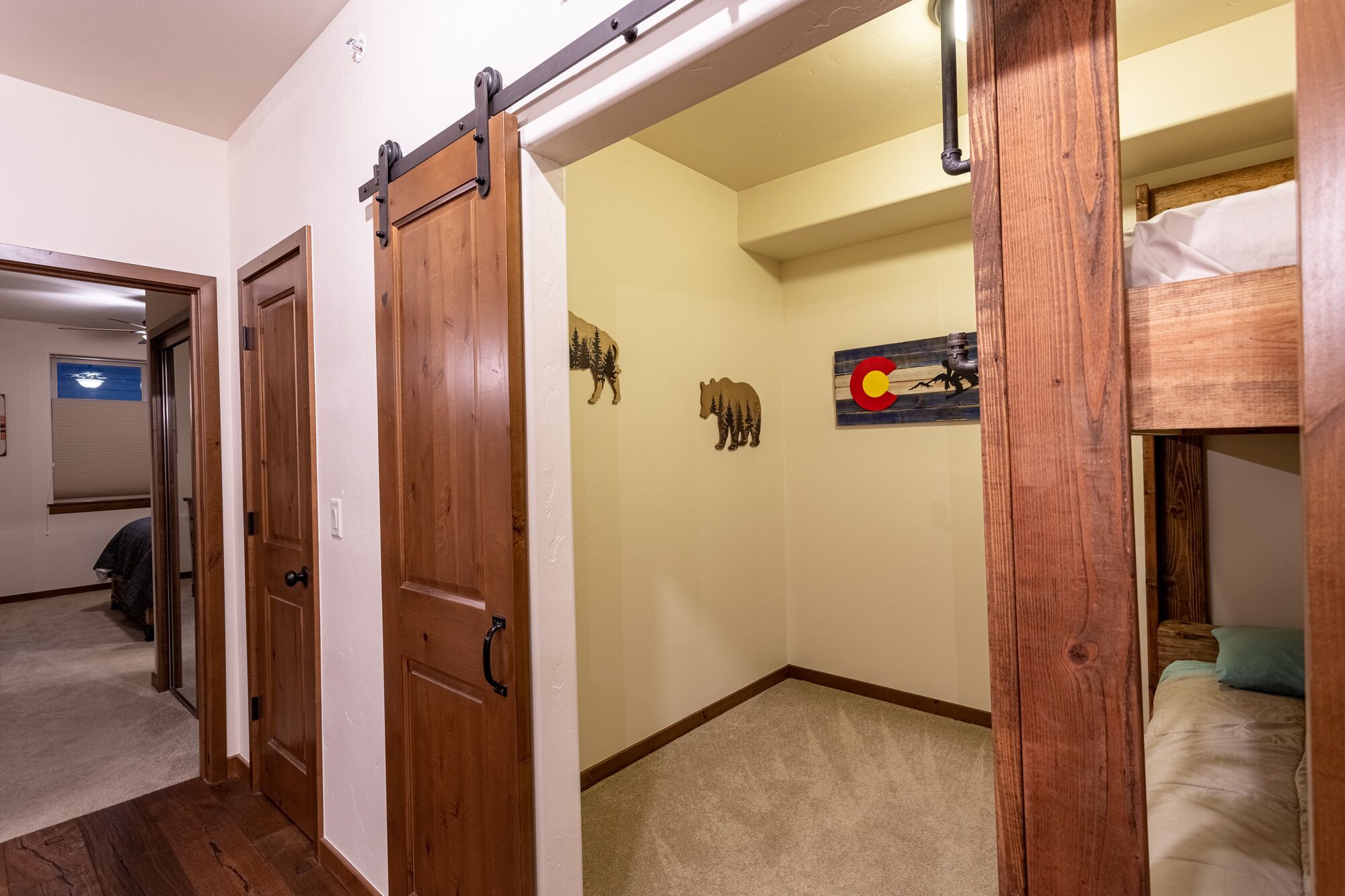 A room with a bunk bed, a sliding door, and a wall with a bear and a flag.