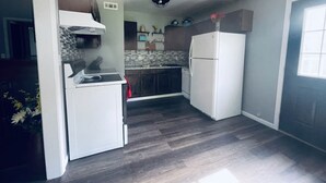 Eine kompakte Küche mit einem weißen Kühlschrank, einem eingebauten Backofen und einer gefliesten Spritzschutzwand.
