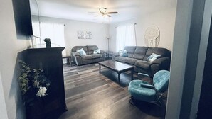 Ein Wohnzimmer mit einer Couch, zwei Sesseln, einem Couchtisch und einem Deckenventilator.