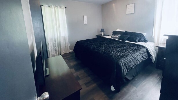 Ein Schlafzimmer mit einem Bett, einem Nachttisch, einer Lampe und einer Kommode.