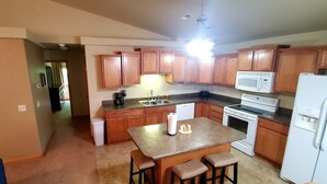 A kitchen with wooden cabinets, a microwave, a stove, and a refrigerator. - Townhouse in a quiet culdesac, easy access to all Black Hills area attractions. (Rapid City)
