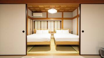 A traditional Japanese-style room with two wooden beds, tatami mats, sliding doors, and a shoji screen.