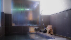 Una vasca idromassaggio con uno sgabello di legno e un tavolino, immersa in piastrelle scure.