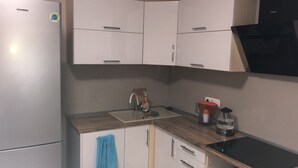 A kitchen with white cabinets, a sink, a stove, and a refrigerator.