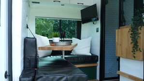 Un intérieur de camping-car moderne et compact, comprenant un coin salon, une petite table et un téléviseur fixé au mur.