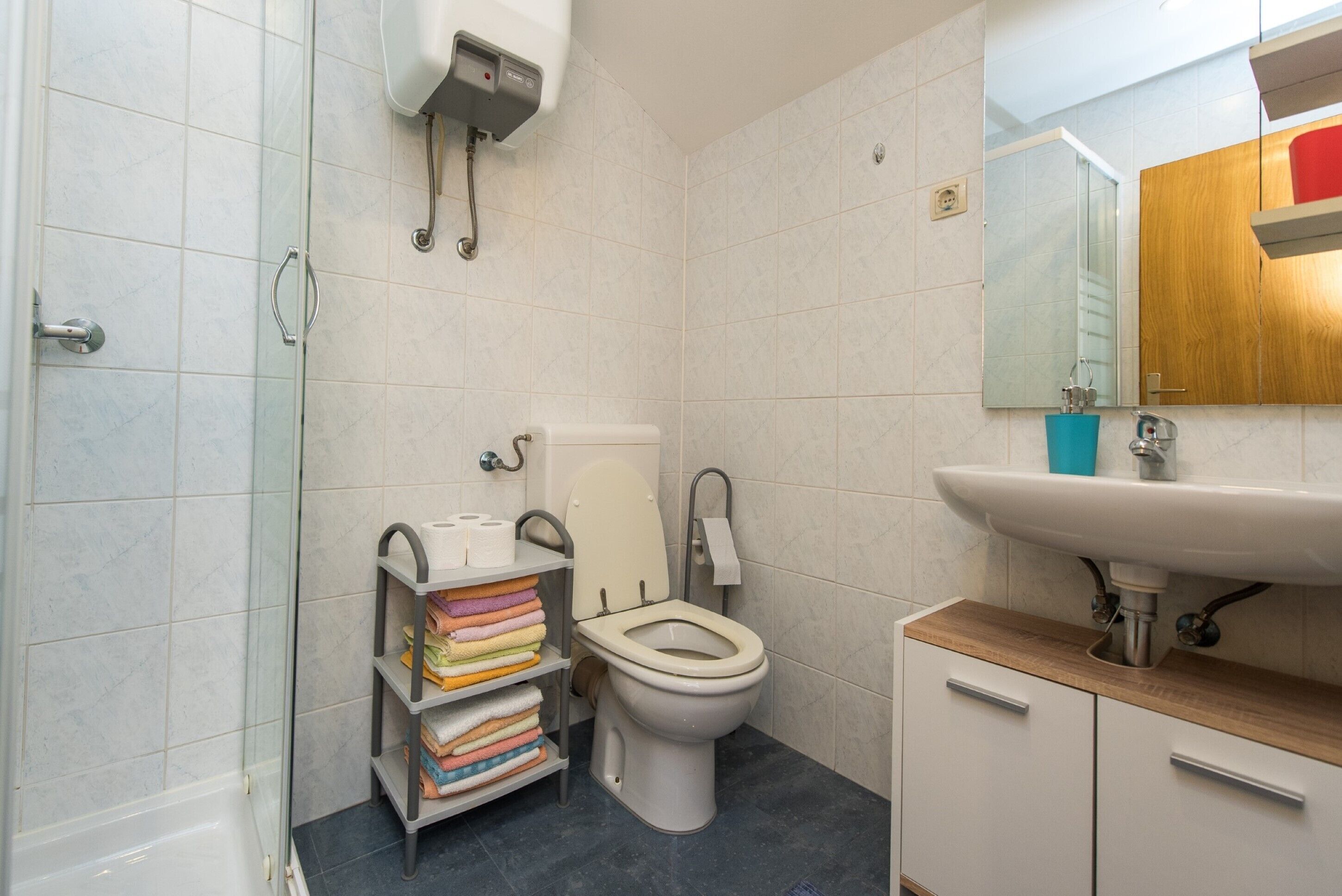 Une salle de bain moderne équipée de toilettes, d’un lavabo et d’une douche à parois de verre.