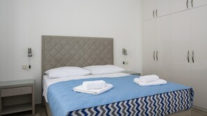 A neatly made bed with a blue and grey chevron-patterned bedspread, white pillows, and folded towels on the side. - A3-90m2 apt w shared pool & balcony,next to beach (Trogir)