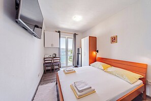 A hotel room with a bed, a desk, a chair, a TV, and a view of the outdoors.