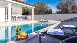 A swimming pool with lounge chairs and a table, surrounded by a covered patio area with chairs and a table. - Beautiful Villa with swimming-pool in Pula Croatia (Pula)