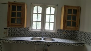 A kitchen with a tiled backsplash, two wooden cabinets, and a double sink. - Summer hill air bnb home away from home (St Ann)