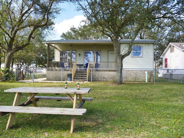 A small house with a porch, fenced yard, and picnic table. - Make Memories and let Your Fun-family Fishing & Hunting Adventure Start Here (Freeport)