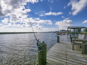 A wooden pier extending into calm water, with a fishing rod and a bottle on the dock. - Make Memories and let Your Fun-family Fishing & Hunting Adventure Start Here (Freeport)