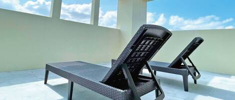 Un área de lounge en la azotea con dos tumbonas y una vista despejada del cielo.
