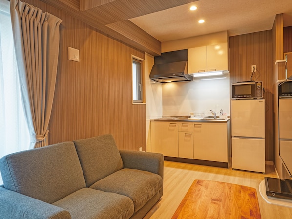 Un espacio habitable pequeño con sofá, kitchenette y paneles de madera.
