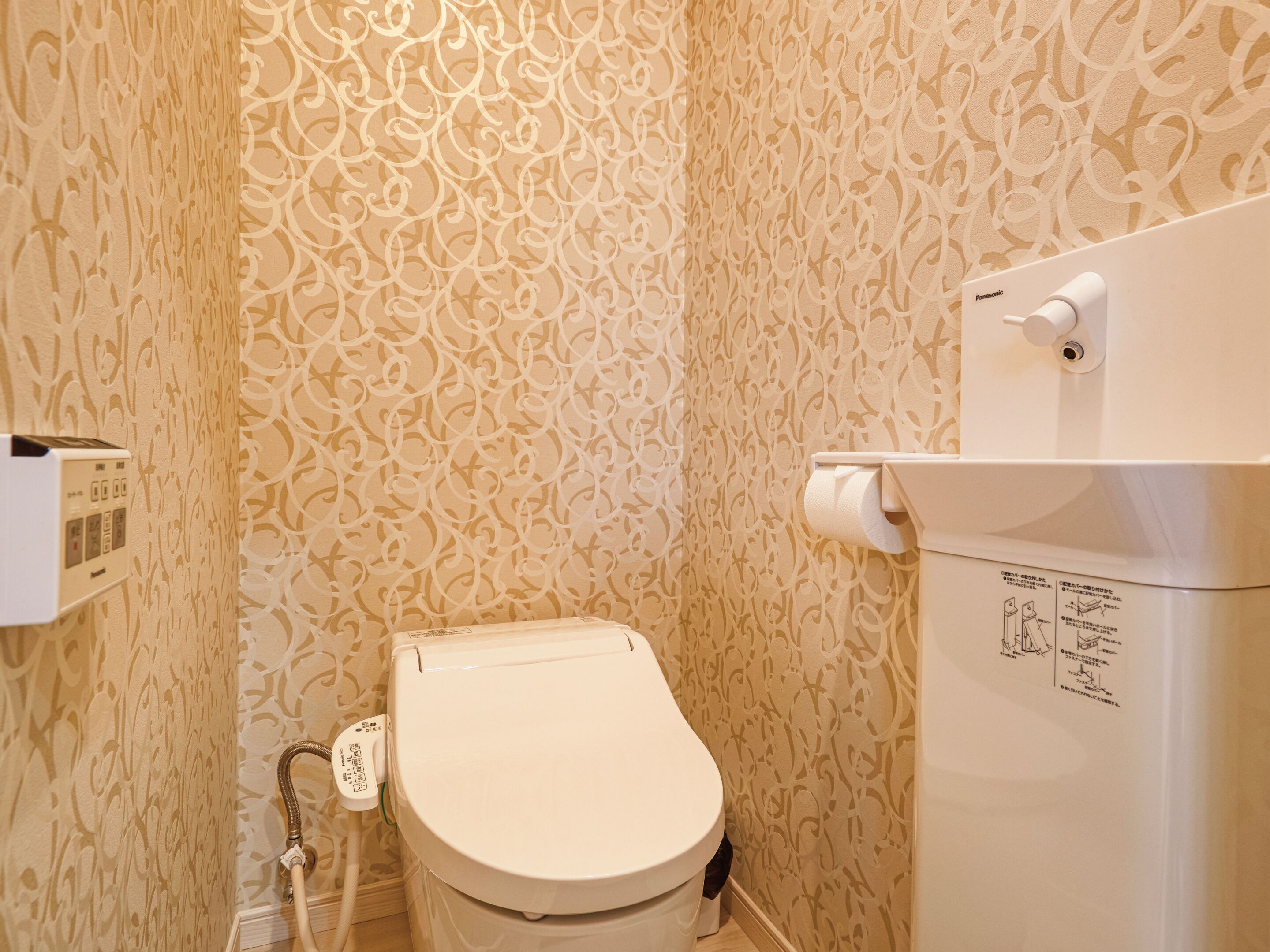 A bathroom with a toilet, a wall-mounted paper towel dispenser, and a toilet paper holder.