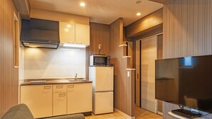 A compact living space with a kitchenette, a flat-screen TV, and a sofa. - Terrace Resort Mihama (Chatan)
