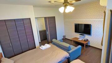 Habitación de hotel con dos camas, un televisor, ventilador de techo y una pequeña mesa.