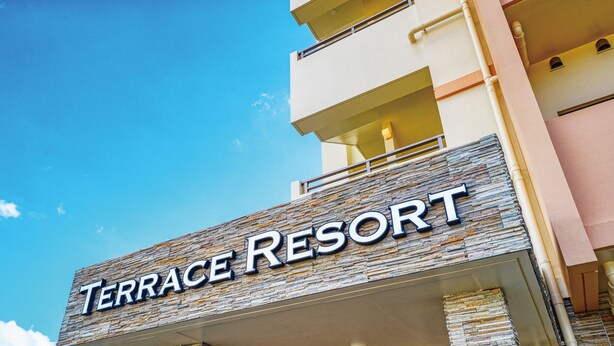 The exterior of Terrace Resort with a stone facade and a clear blue sky. - Terrace Resort Mihama (Chatan)