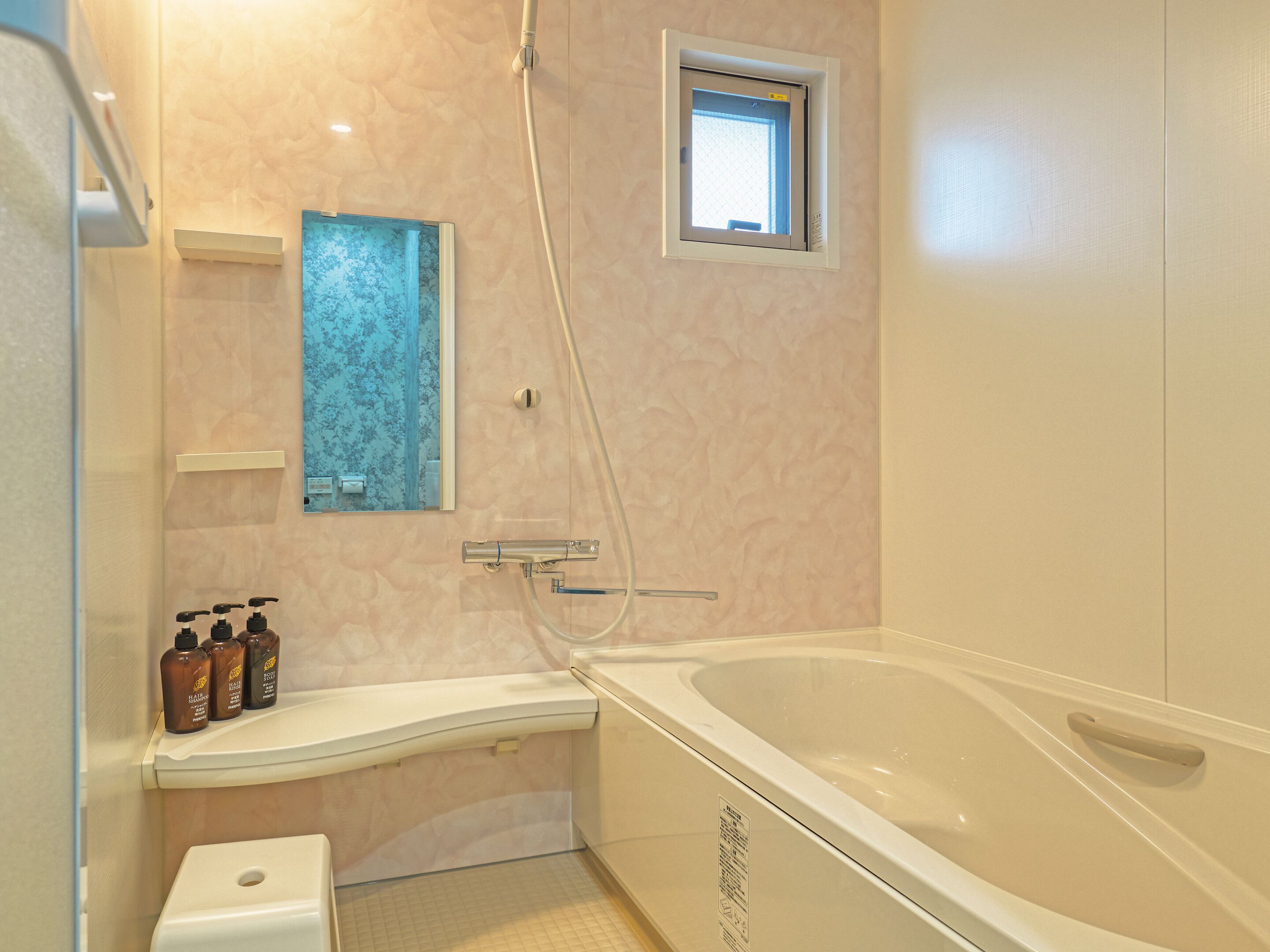 A bathroom with a bathtub, a shower, and a toilet. There are three bottles on the counter.