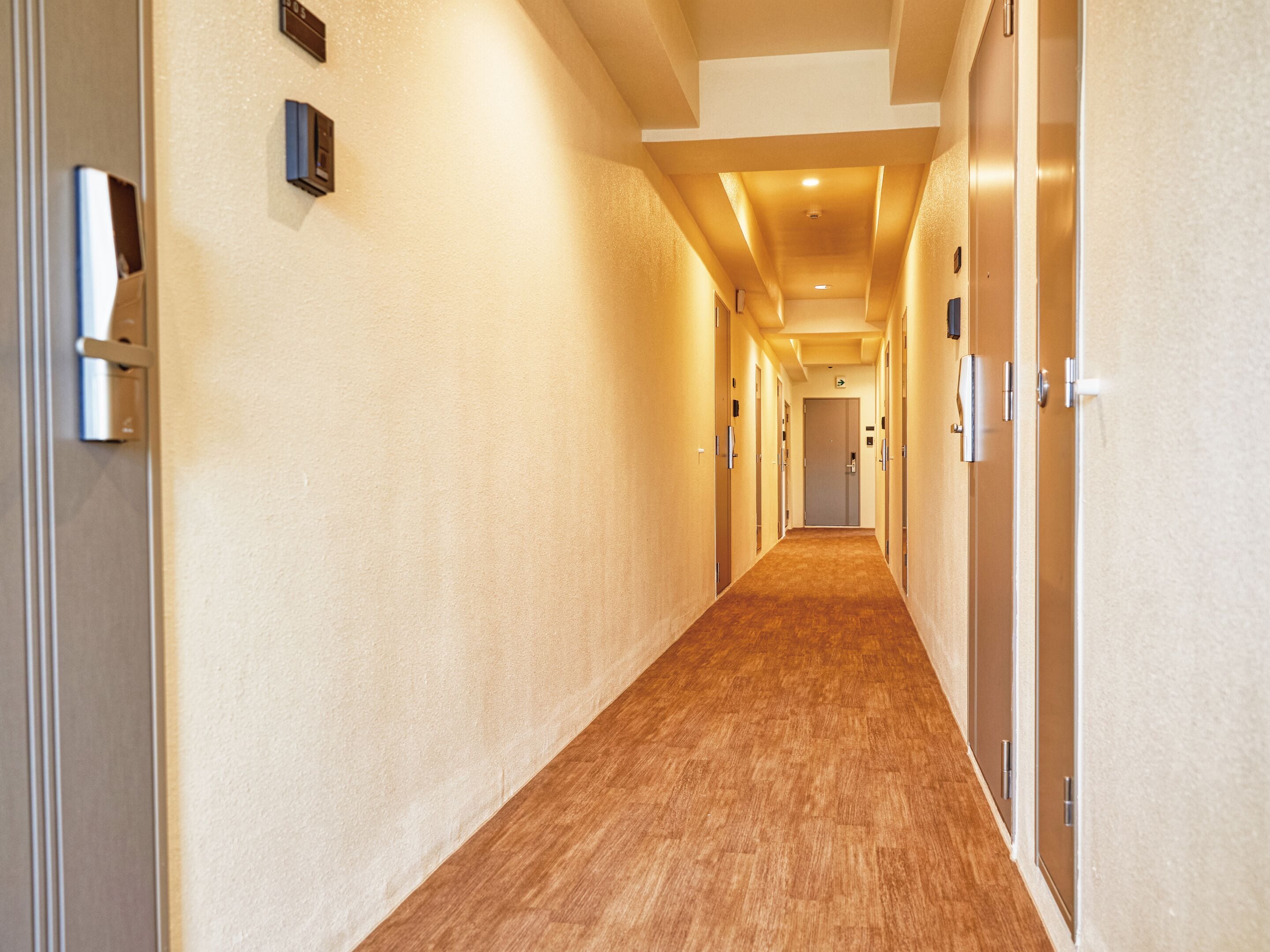 Un pasillo largo y estrecho con suelo de madera y paredes color beige.