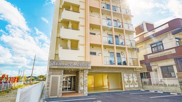 Un hotel de varios pisos llamado Terrace Resort, con un diseño moderno, varios balcones y un cielo despejado.