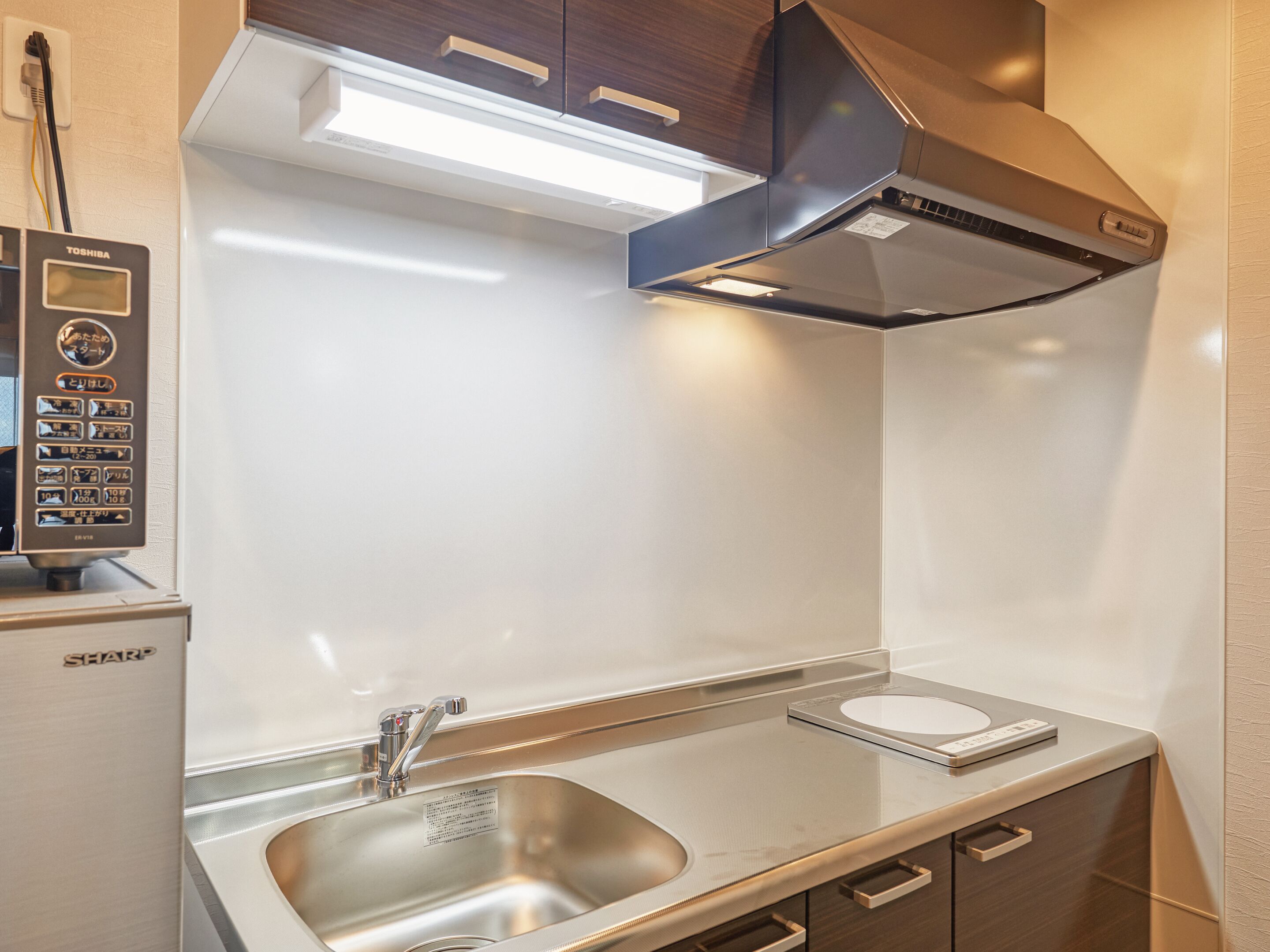 A modern kitchen with a stainless steel sink, a built-in oven, and a digital control panel.