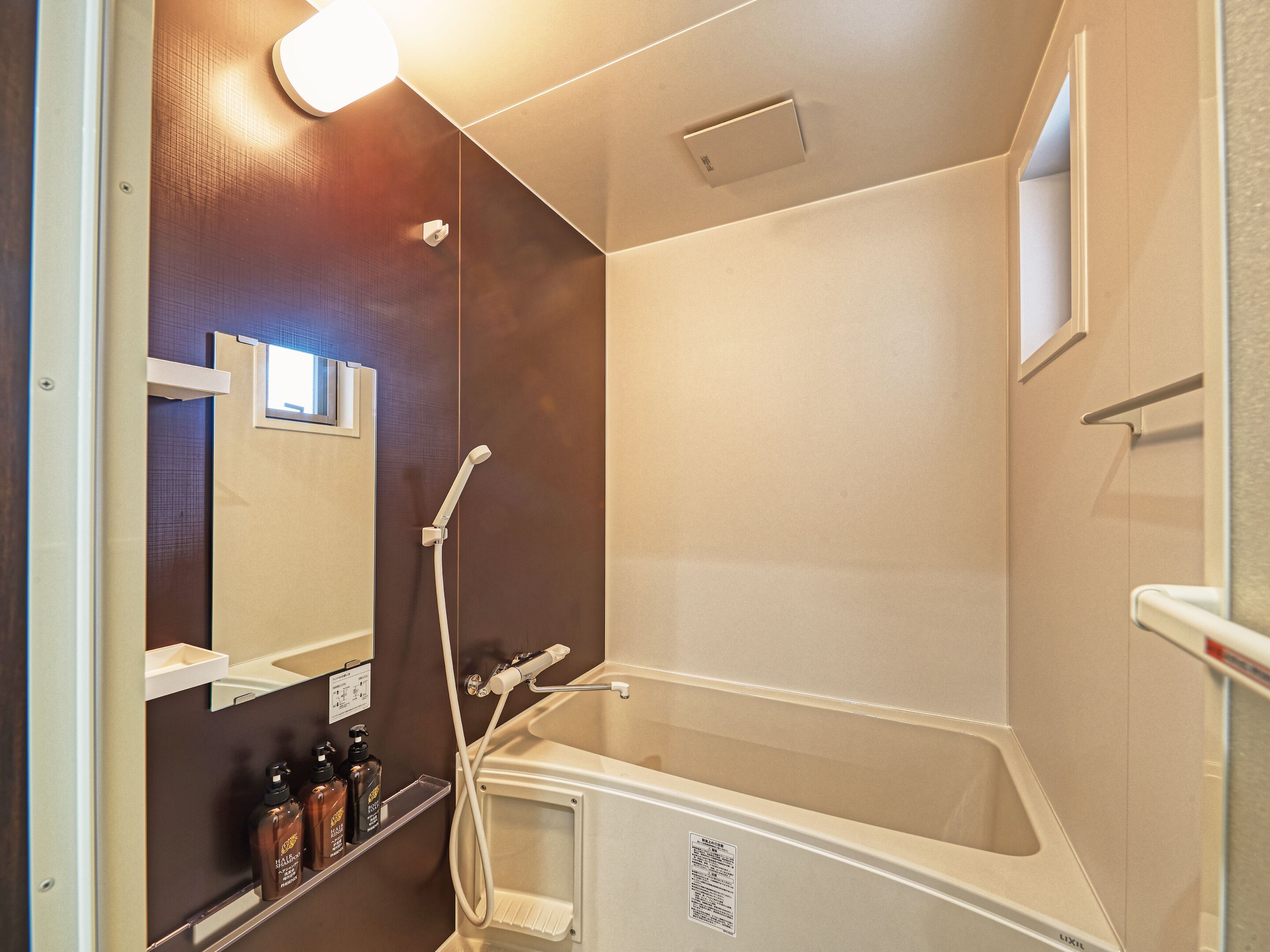 A modern bathroom with a bathtub, a handheld showerhead, a wall-mounted mirror, and a shelf with toiletries.