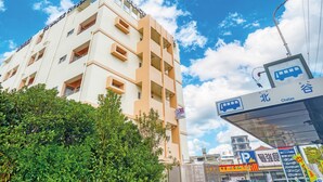 Un hotel llamado "Hotel Terrace" con varios pisos y balcones, rodeado de vegetación y un cielo azul despejado.