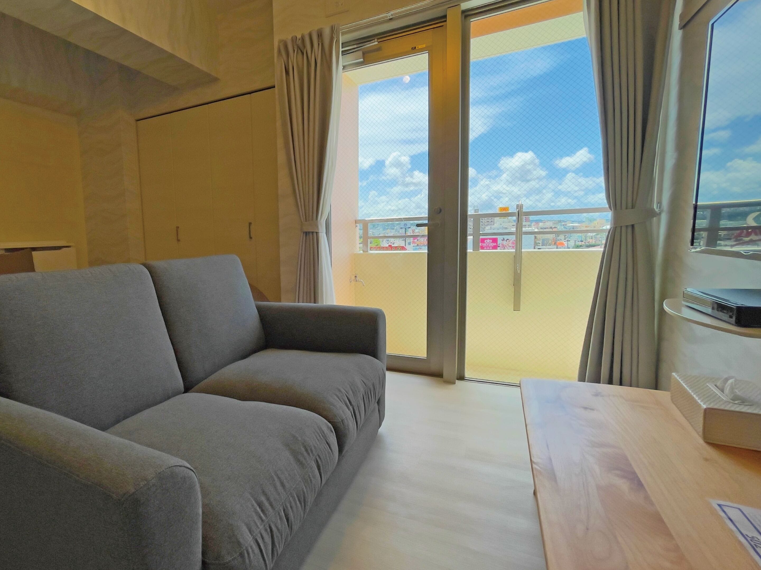 Una sala de estar moderna con un sofá gris, una mesa de madera y un balcón con vistas a la ciudad.