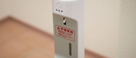 A hand sanitizer dispenser with a warning label in a foreign language.