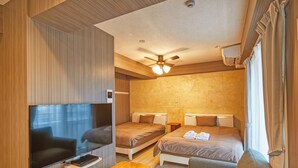 A modern hotel room with a flat-screen TV, two beds, a ceiling fan, and a wooden bench. - Terrace Resort Mihama (Chatan)