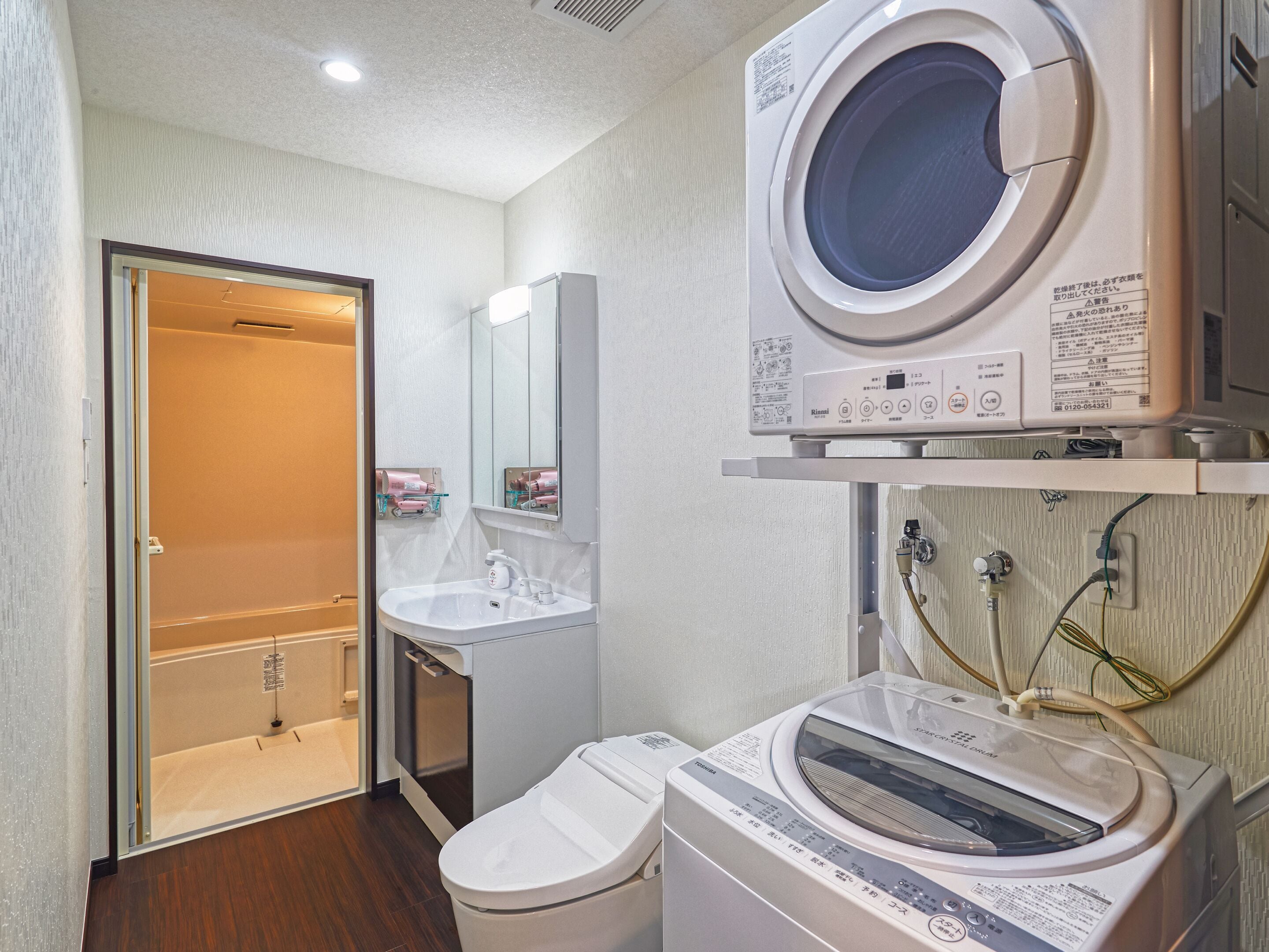 Un bagno d'albergo compatto con lavatrice, lavandino e water.