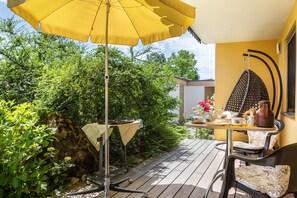 A patio with a yellow umbrella, a table with chairs, and a hanging chair. - Bed and Breakfast at Gertrud's with Garden, Terrace & Playground (Hergensweiler)