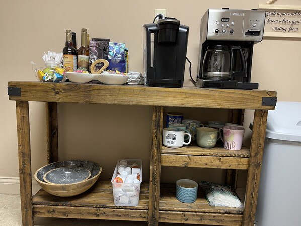 Una mesa de madera con una cafetera, un bol y varias tazas y recipientes.