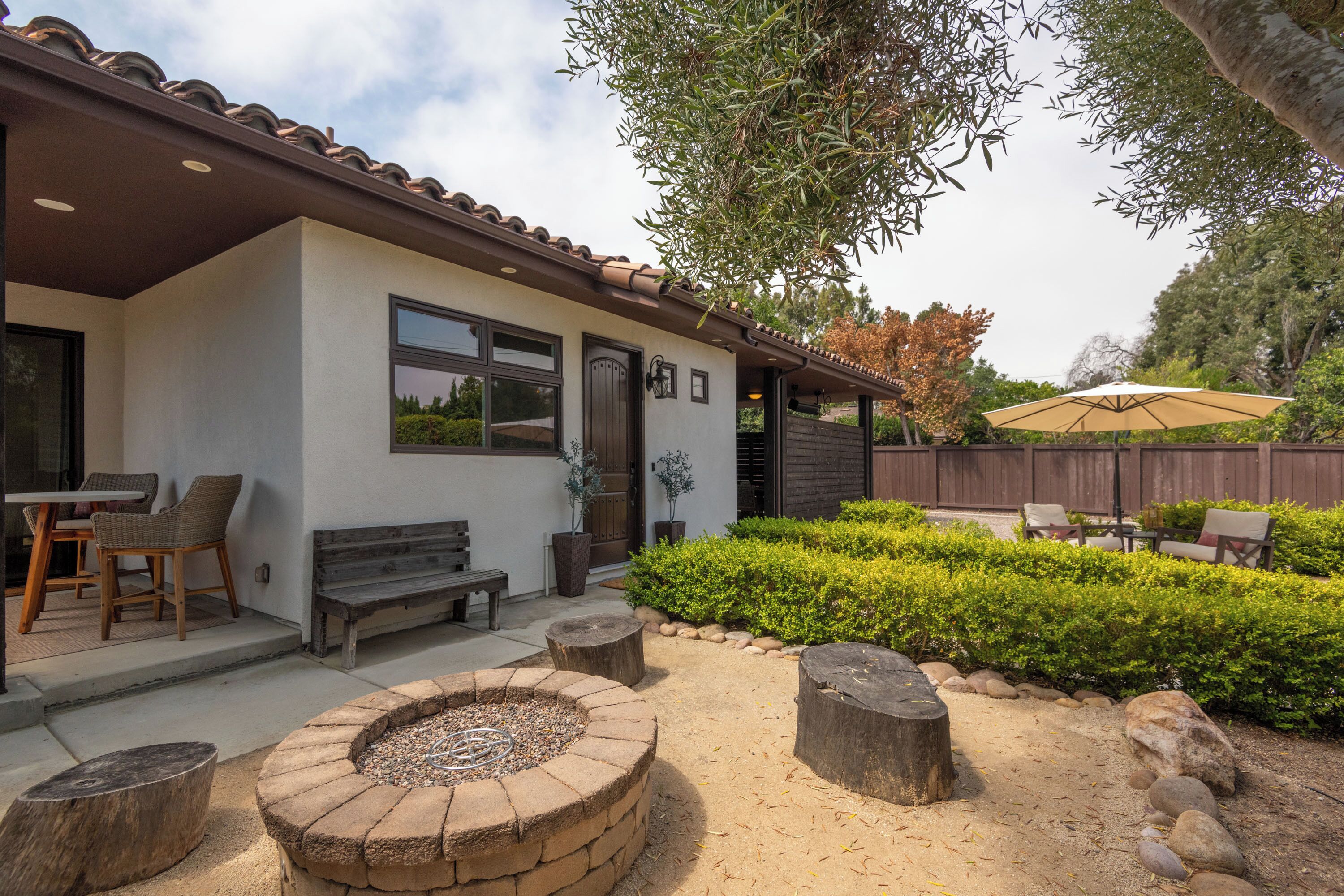 A house with a patio, outdoor seating, a fire pit, and a well-maintained garden.