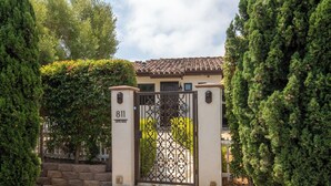 A gated entrance with a stone pathway leading to a building with a tiled roof. - Capri Coastal Tuscan Getaway – Ideal for Extended Stays! (Encinitas)
